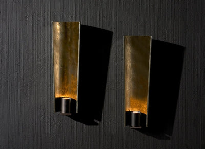 Two elegant gold wall sconces on a black wall, crafted by Artisan Lighting Company, enhancing the room's ambiance.