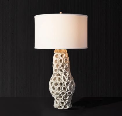 Artistic table lamp with sculptural white ceramic base and classic drum shade