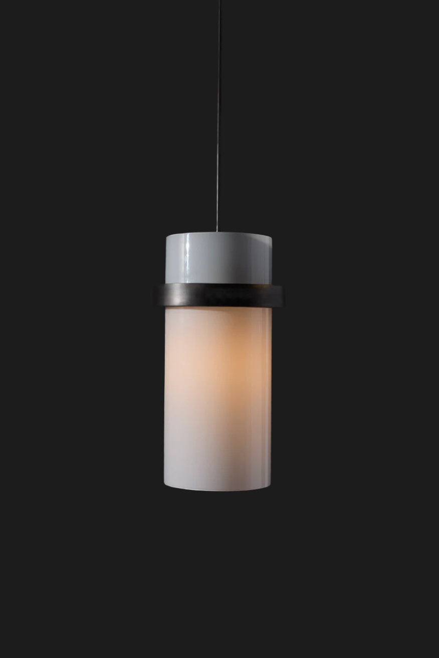 white glass cylinder shaped lighting fixture with brass ring illuminated on grey background