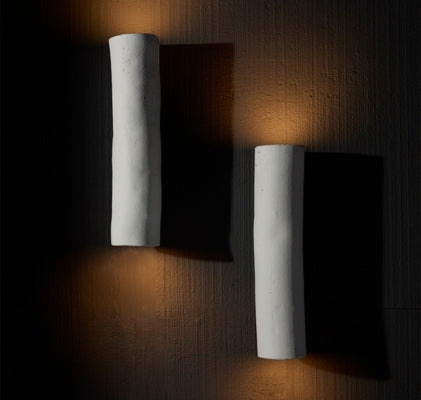 Italian sculptural wall sconces with textured white finish, casting warm indirect light for modern interiors.