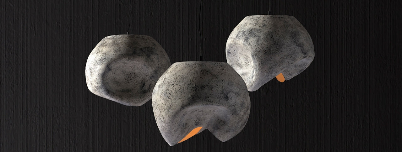 Italian sculptural pendant lights with organic stone-inspired forms, casting warm indirect ambient illumination.
