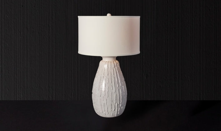 Elegant Italian ceramic table lamp with textured sculptural base and white drum shade for refined ambient lighting.
