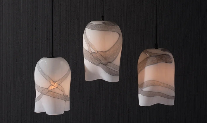 Three elegant glass pendant lights suspended against a sleek black wall, showcasing luxury home custom lighting design.