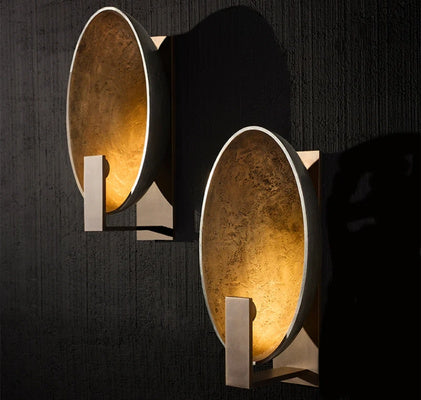 Two stylish wall sconces with gold detailing on a black wall, exemplifying luxury in custom home lighting.