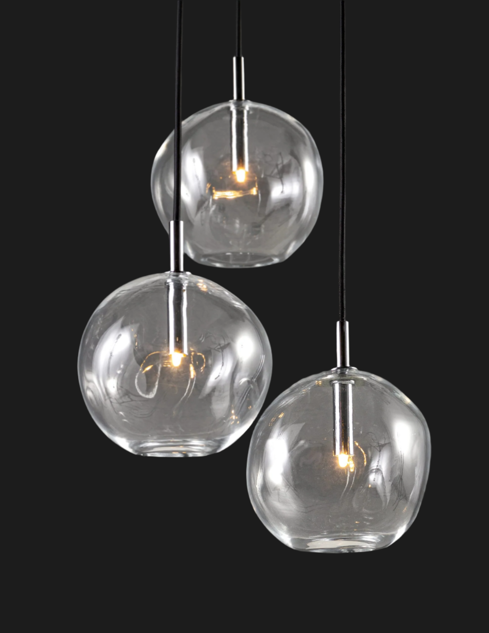 triple globe shaped glass lighting fixture illuminated on grey background