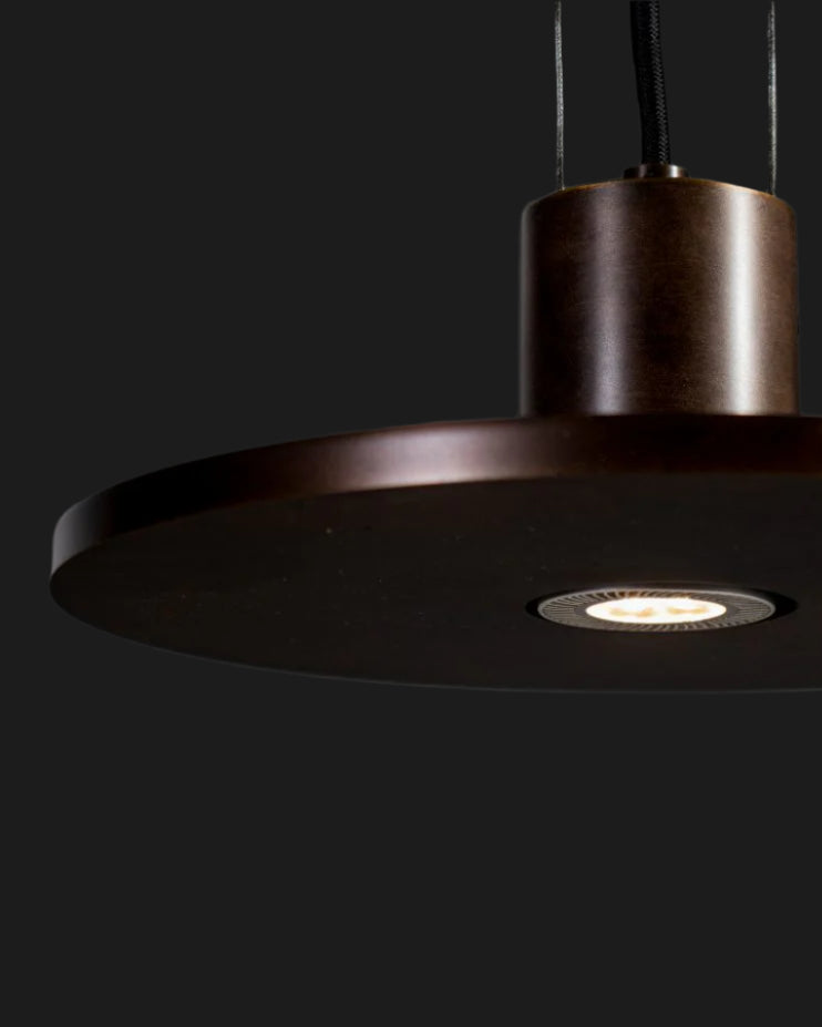 metal disk lighting fixture illuminated on black background