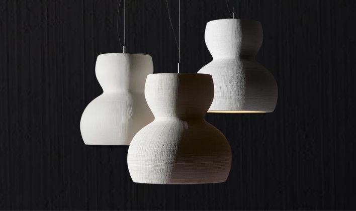 Artistic light fixtures with three sculptural white pendant lamps on a dark background