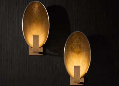 Artistic metal wall sconces with oval gold-toned reflectors and warm ambient light