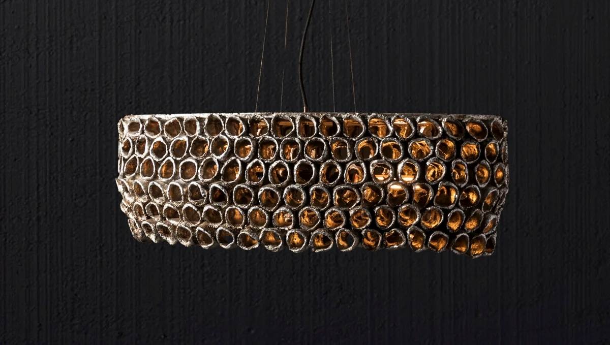 Handmade textured drum pendant light with mosaic glass detailing, emitting warm ambient glow for statement interiors.