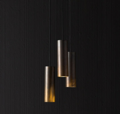 Italian cylindrical metal pendant lights with warm downward glow, offering sleek modern architectural lighting.
