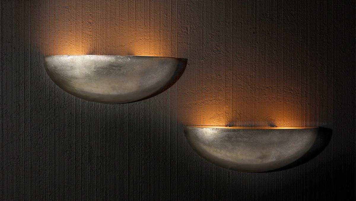 Pair of Italian half-moon metallic wall sconces casting warm indirect light for sophisticated architectural interiors.